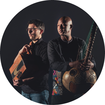 Cyrille Brotto looks off while he holds an accordion next to Abalye Cissoko holding a kora in front of him.