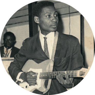 Black & White photo of a young Pat Thomas playing an electric guitar in the foreground.