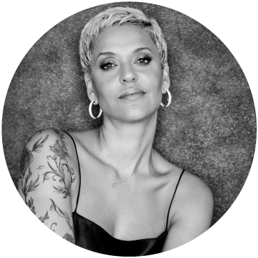 Black and white photo of singer Mariza in a dress smirking.