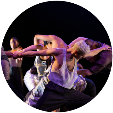Three dancers wearing silver and black grab each other by the wrists and back to form a circle of limbs.