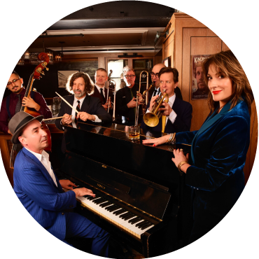 Eight members of the Hot Sardines pose together in a jazz cafe as they play their instruments.