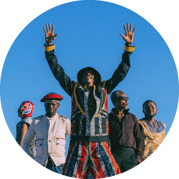 upiter Bokondji Ilola stands in the middle of his band Okwess, with his arms and hands extended against a blue background.