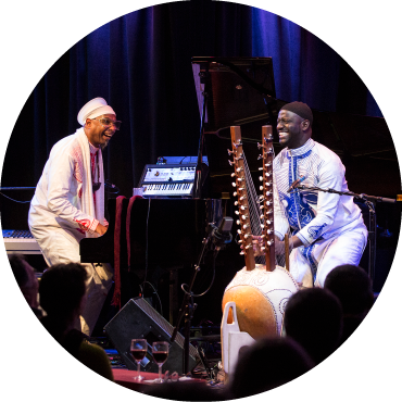 Omar Sosa (left) plays the guitar next to Seckou Keita (right) playing the kora on stage