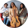 Subhasis, Debashish and Anandi Bhattacharya smile on a red couch and hold a drum, slide guitar, and swarmandal (small harp) against a blue background.